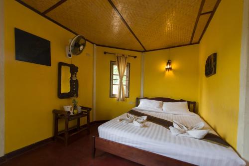 a bedroom with a white bed with a yellow wall at The Countryside Pai in Pai