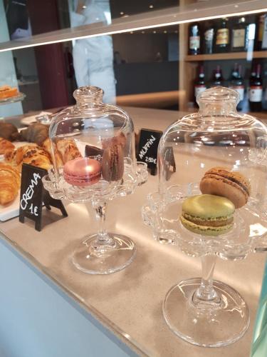 a display of cakes and pastries in glass containers on a counter at Hotel Oleggio Malpensa in Oleggio