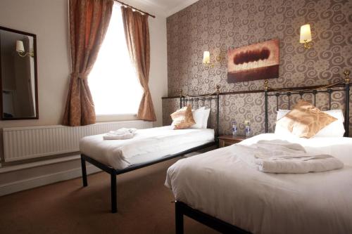 a hotel room with two beds and a window at White Hart, Andover by Marston's Inns in Andover