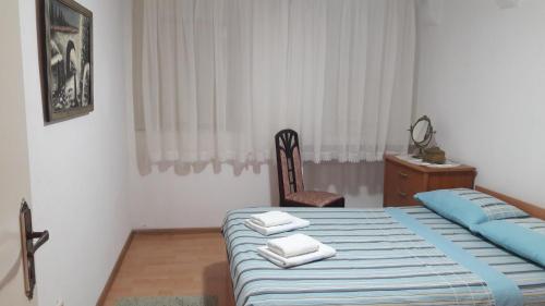 a bedroom with a bed and a chair with towels on it at Apartment VASSA in Kotor