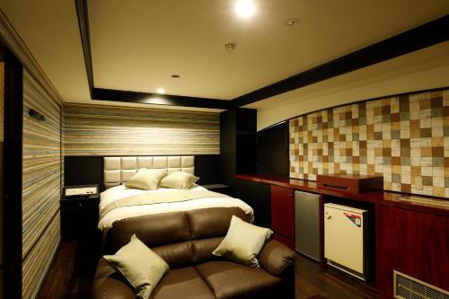 a bedroom with a bed and a couch at ホテル マリオン 鈴鹿 in Suzuka
