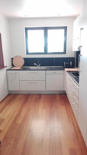 a kitchen with white cabinets and a wooden floor at Casa dos Arcos in Caramulo