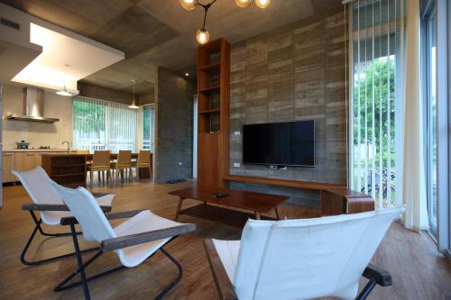 a living room with white chairs and a flat screen tv at Chuying Sunrise B&B in Jian