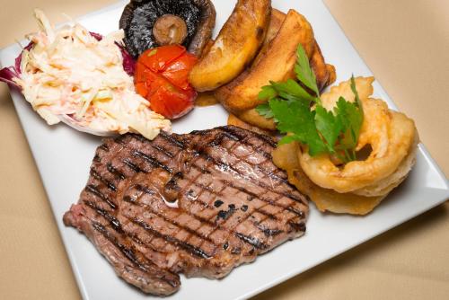 a plate of food with steak and other foods at Ocean View Hotel in Shanklin