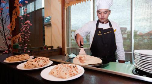 un chef de pie en una cocina preparando comida en Hotel Seri Malaysia Lawas, en Lawas