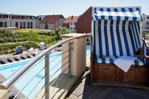 a deck with a beach chair and a swimming pool at Strandhotel Georgshöhe in Norderney
