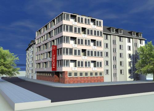 a tall white building with a red sign on it at KEMPE Komfort Hotel in Düsseldorf