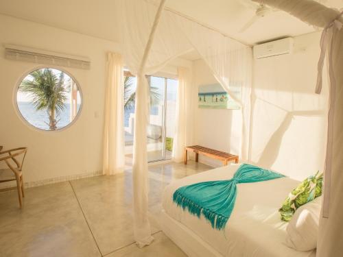 1 dormitorio con cama blanca y ventana en Bahia Mar Beach House, en Vilanculos
