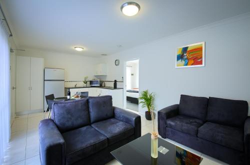 a living room with two couches and a kitchen at Pelicans Albany Middleton Beach in Albany