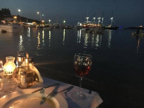 a glass of wine sitting on a table next to the water at Pappou's Studios in Ormos Panagias