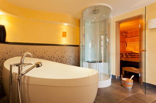a bathroom with a bath tub and a shower at Strandhotel Georgshöhe in Norderney