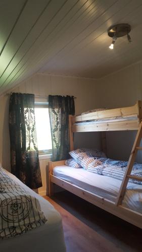 a bedroom with two bunk beds and a window at Grimsøy Lofoten House in Saupstad
