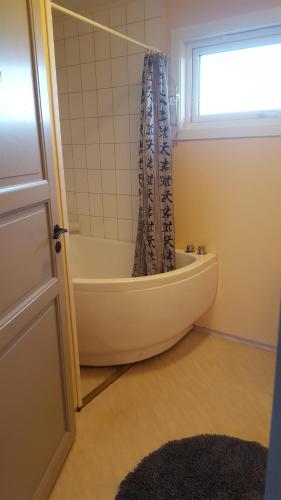 a bathroom with a tub and a shower curtain at Grimsøy Lofoten House in Saupstad