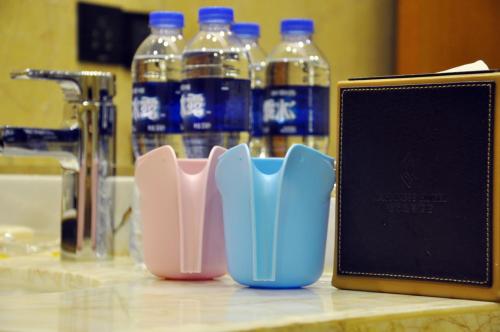 a counter with a toothbrush holder and bottles of water at Happiness Hotel in Changzhou