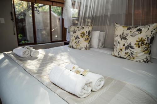 Una cama blanca con toallas y almohadas. en Raptors Lodge, en Hoedspruit