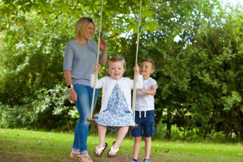 a woman and two children on a swing at Heacham Manor Hotel in Hunstanton