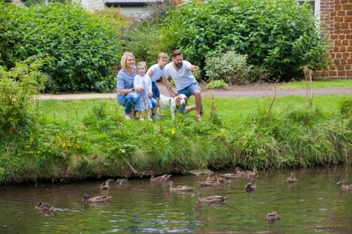 a family sitting next to a pond with ducks at Heacham Manor Hotel in Hunstanton