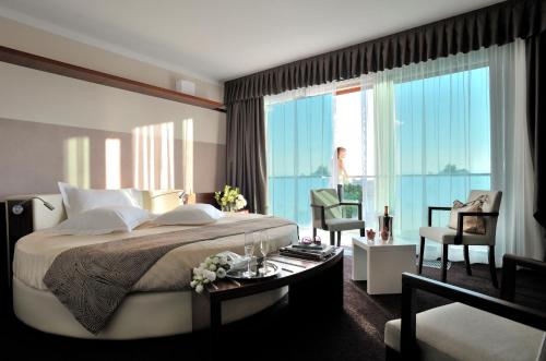 a bedroom with a large bed and a large window at Aqualux Hotel Spa Suite & Terme in Bardolino