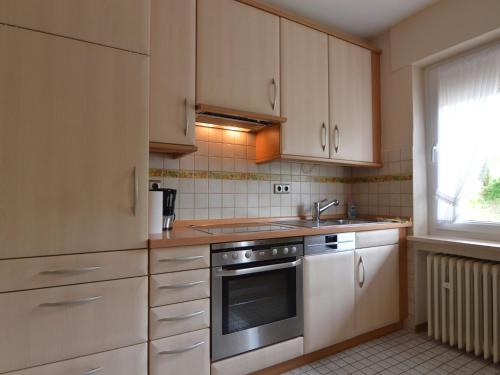 a kitchen with white cabinets and a sink and a window at Holiday home in Densborn with garden in Zendscheid