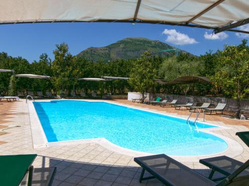 a swimming pool with chairs and a mountain in the background at Belvilla by OYO Mandarino in San Cipriano Picentino