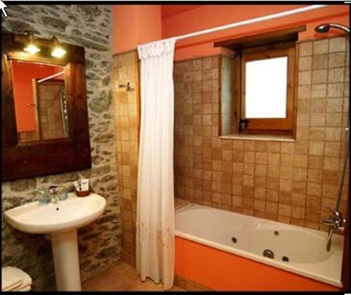 y baño con lavamanos, bañera y lavamanos. en Hotel El Jaç, en Ger