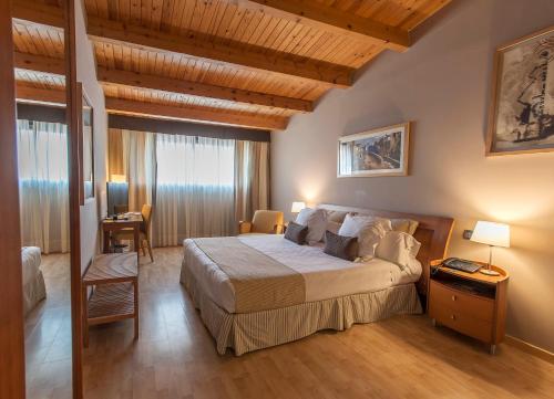 Un dormitorio con una cama grande en una habitación con techos de madera. en Estela Barcelona, en Sitges