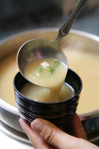 a person holding a bowl of soup with a spoon at Kansyokan in Mogami