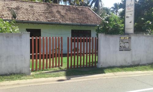 a fence in front of a small house at SunRay Rest - Beach View Homestay in Mirissa