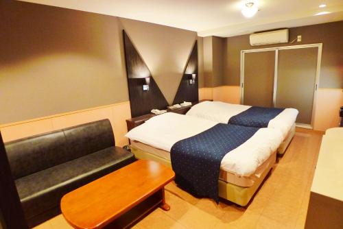 a hotel room with two beds and a couch at Hotel Times Inn 24 in Yokohama