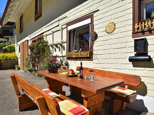 una mesa de madera con una botella de vino y dos bancos en Country style flat with garden, en Triberg