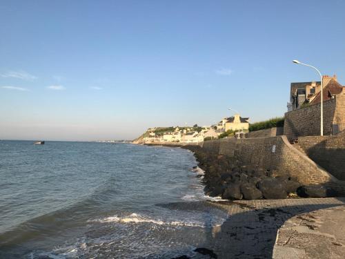 a beach with houses and the ocean on a sunny day at Vue mer à Arromanches in Arromanches-les-Bains