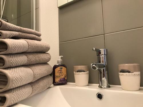 ein Waschbecken mit Handtüchern und einem Spiegel in der Unterkunft Vue mer à Arromanches in Arromanches-les-Bains