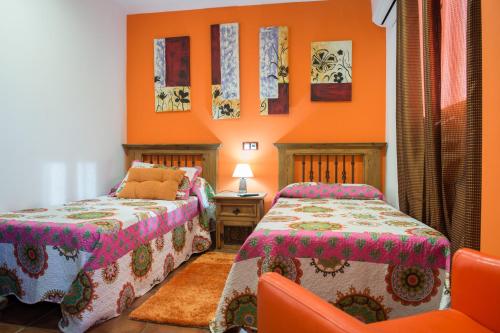 2 camas en una habitación con paredes de color naranja en Hostal Restaurante Rijujama, en Matillas