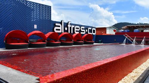 a swimming pool with red chairs in front of a building at Alfresco Phuket Hotel in Patong Beach