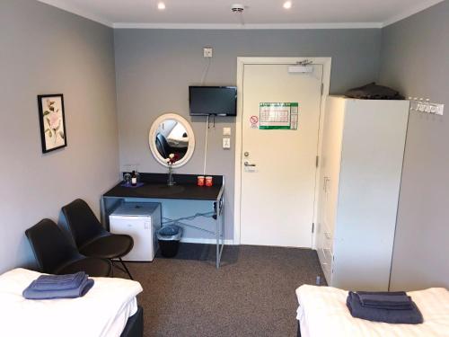 a room with two beds and a desk and a mirror at Motell Trafikanten in Bygdeå