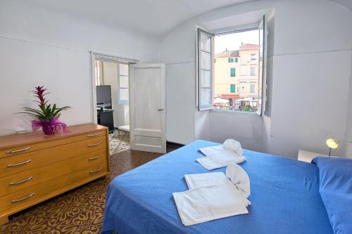 a bedroom with a blue bed and a dresser and a window at Casa del Borgo in Finale Ligure