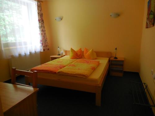 a bedroom with a bed with yellow sheets and a window at Penzion Tisuvka in Cikháj
