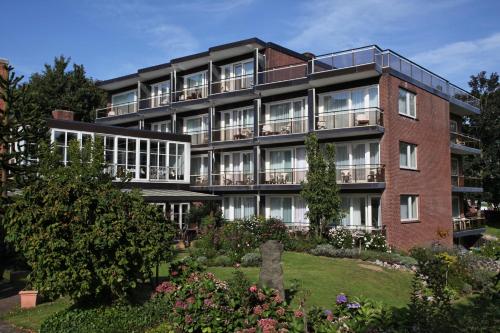 an apartment building with a garden in front of it at Hotel Wehrburg in Cuxhaven