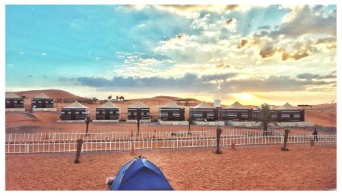 a tent in the desert with buildings in the background at Bedouin Oasis Desert Camp- Ras Al Khaimah in Ras al Khaimah