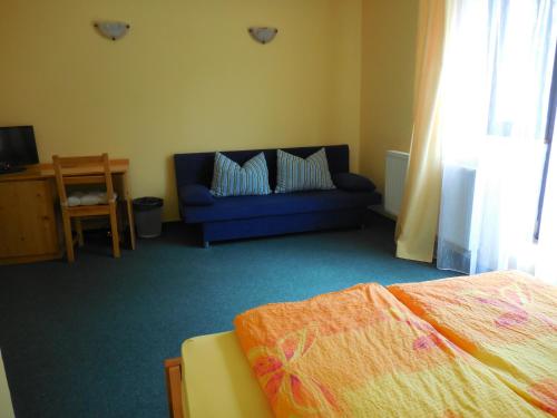 a bedroom with a bed and a blue couch at Penzion Tisuvka in Cikháj