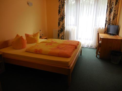 a bedroom with a bed and a window with a television at Penzion Tisuvka in Cikháj