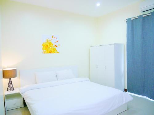 a bedroom with a white bed and a blue curtain at Sunee View Hotel in Chachoengsao