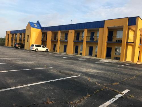 a yellow building with a car parked in a parking lot at Knights Inn Lumberton in Lumberton