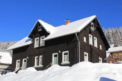 a black house with snow on the roof at Ferienhaus Anno Dazumal, wie zu Oma`s Zeiten in Klingenthal