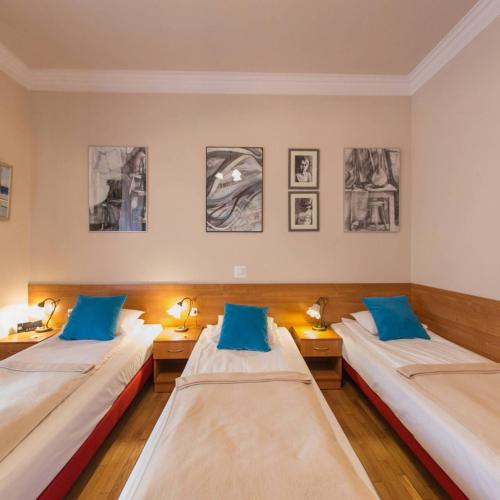 dwa łóżka w pokoju z obrazami na ścianie w obiekcie Apartamenty Kajzer w Krakowie