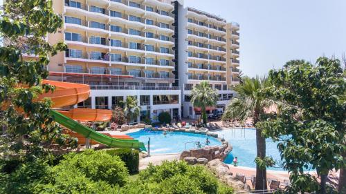 a resort with a swimming pool and a large building at Palmin Hotel in Kusadası