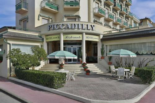 a patio with umbrellas and chairs in front of a building at Hotel Piccadilly in Lido di Camaiore