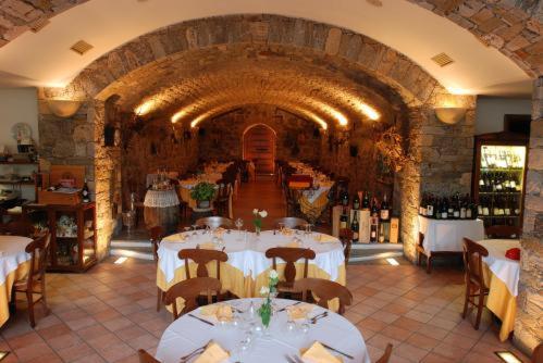 a restaurant with white tables and bottles of wine at Residence Antico Crotto in Porlezza