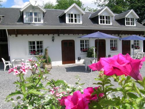 a white house with pink flowers in front of it at Apartment situated on a magnificent estate in Barvaux