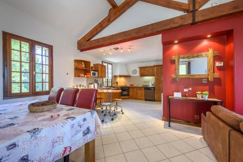 une cuisine et une salle à manger avec un mur rouge dans l'établissement Gîte Le Planier, à Saint-Priest